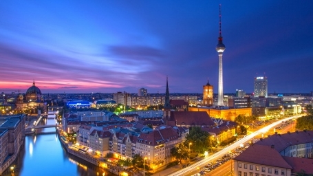 Aerial shot of the city of Berlin showing a river, buildings, monuments, and the Berlin TV Tower.